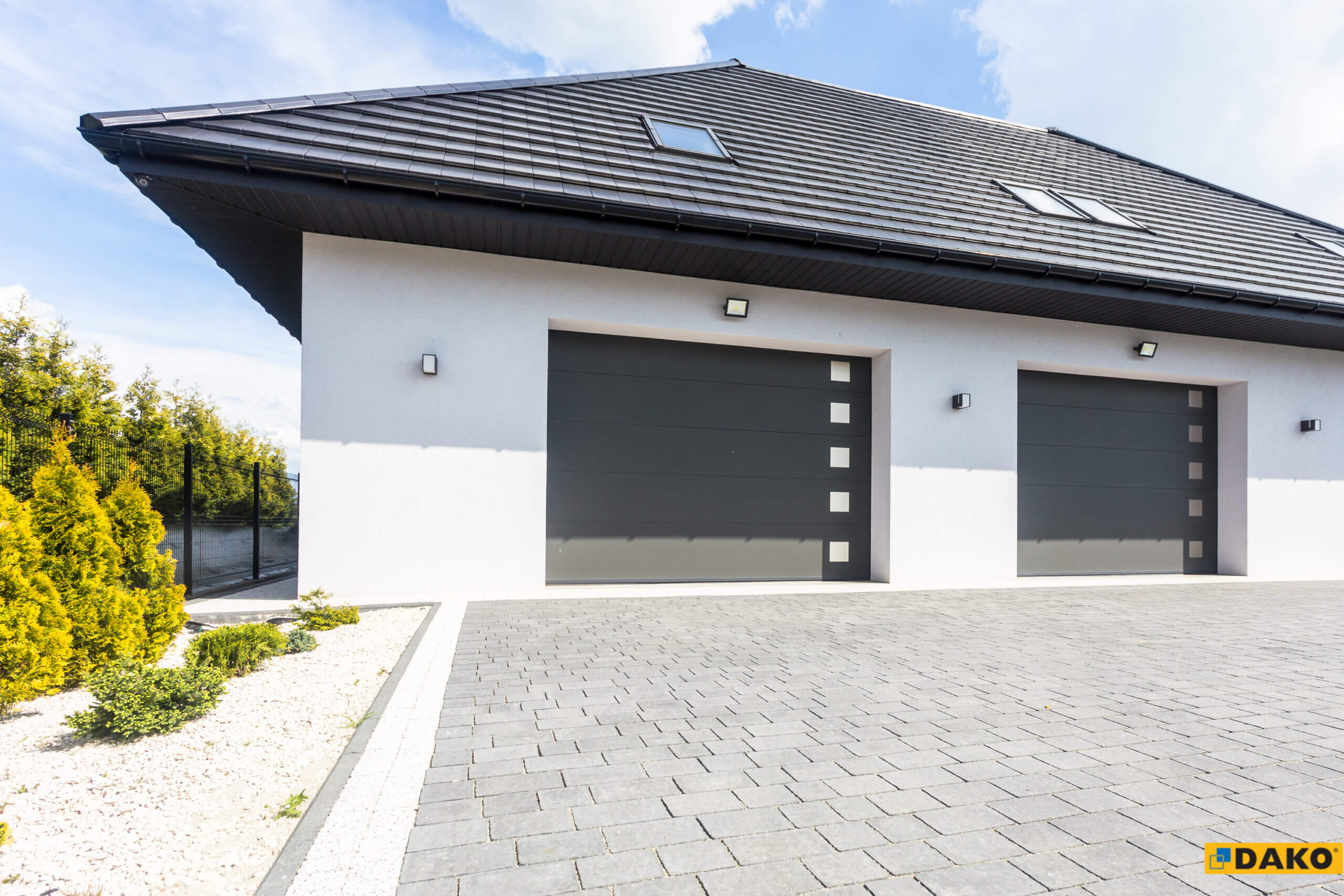 Deux portes de garage sectionnelles grises posées sur une maison